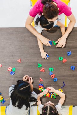 Düz yatıyordu shot birinin Asya öğrenciler sınıf birlikte, konsepti ile renkli alfabesi harfleri oyuncak oyun.
