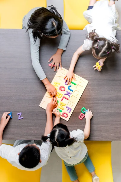 平板电视的亚洲老师玩五颜六色的字母表木块与亚洲学生在一起 概念为教室 — 图库照片