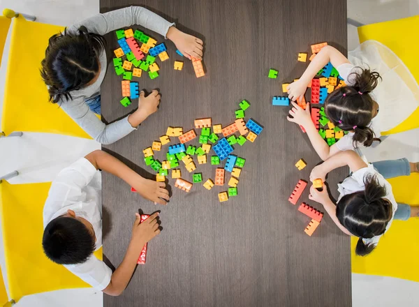 Group of kids and teacher playing colorful toys in classroom. Concept for happy and funny learning, brain development activities in school free time.