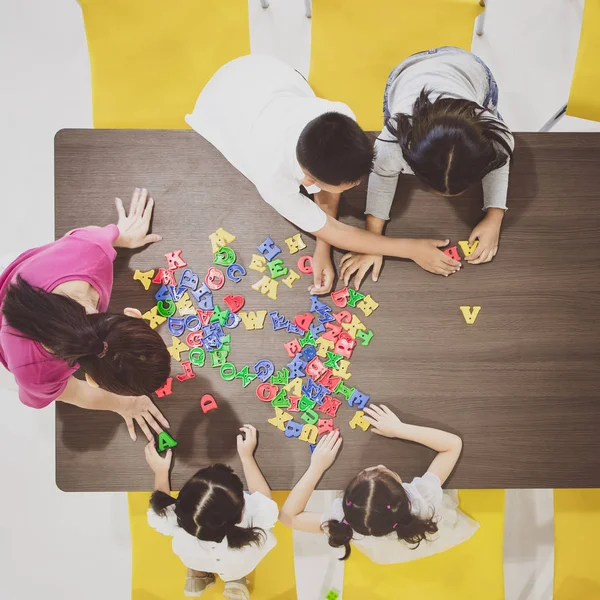 Çocuklar ve öğretmenler sınıfta renkli oyuncaklar oynuyorlar. Okul boş zamanlarında mutlu ve eğlenceli öğrenme, beyin geliştirme aktiviteleri kavramı.