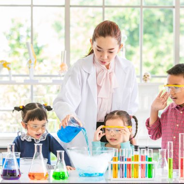 Fen bilgisi öğretmeni cam kase, renkli tüp ve laboratuvar Oda tabloda, kavram mikroskobunun çalışma laboratuvar odasında için Asya öğrenciler kimyasallar, öğretmen pour kimyasallar hakkında öğretmek.