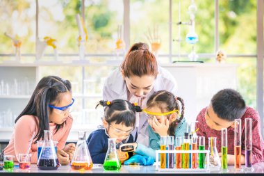 Fen bilgisi öğretmeni öğretmek laboratuvar odasında, öğretmen kullanım büyüteç ile bir şey, Asya öğrenciler renkli tüp ve tablo, laboratuvar Oda çalışmada için kavram mikroskobunun.