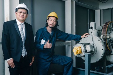 Asya çift mühendis ve birlikte duran genç bir mühendis ve kamera için gülümseme, büyük planı elinde, endüstriyel fabrika mühendisi için kavram tutar.