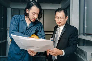 Asya çift mühendis ve genç bir mühendis blueprint görünüm ve birlikte, endüstriyel fabrika mühendisi için kavram tartışmak.