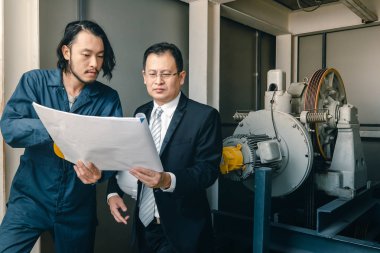 Asya çift mühendis ve genç bir mühendis blueprint görünüm ve birlikte, endüstriyel fabrika mühendisi için kavram tartışmak.