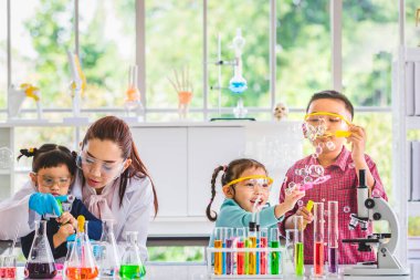 Fen bilgisi öğretmeni ve laboratuvar odasında Asya öğrenciler, onlar kabarcıklar, üfleme renkli tüp ve laboratuvar Oda, kavram için tabloda mikroskobunun laboratuvar içinde çalışma odası.