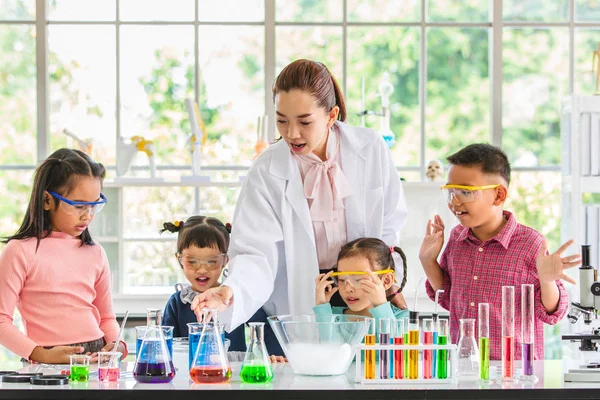 科学老师在实验室里教亚洲学生化学药品 五颜六色的试管和桌子上的显微镜 实验室学习的概念 — 图库照片