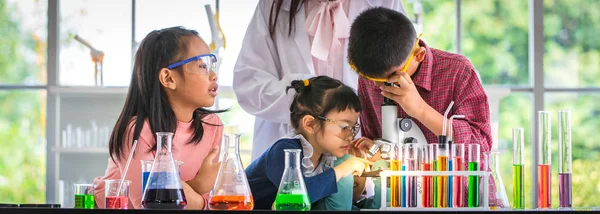 理科の先生が研究室 顕微鏡 カラフルな試験管と顕微鏡 研究室での研究のための概念のテーブルの上を見上げる少年のアジア学生を教える — ストック写真