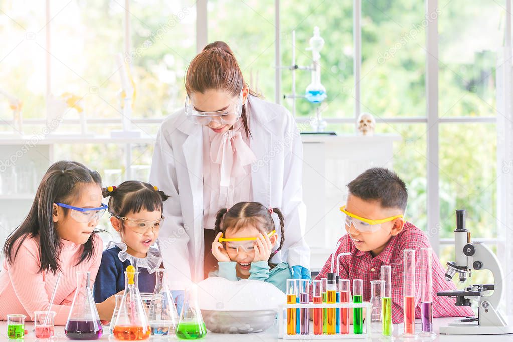 Science teacher teach Asian students in laboratory room, smoke float out of bowl, they excited, colorful test tube and microscope on table in laboratory room, concept for study in laboratory room.