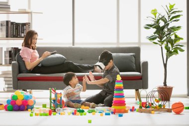 Asya Aile, tablet şakacı kanepeye, Genç çocuk giyim beyaz taklit Oyunlar gözlük kulaklık kullanma ev, genç güzel annem, rahatlatıcı, happy Time'da touch elleriyle küçük sevimli bebek