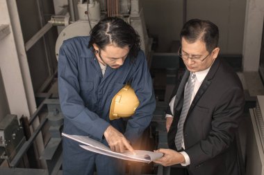 Asya çift mühendis ve genç bir mühendis blueprint görünüm ve birlikte, endüstriyel fabrika mühendisi için kavram tartışmak.