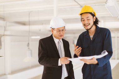 Asya çift mühendis ve genç bir mühendis blueprint görünüm ve birlikte, endüstriyel fabrika mühendisi için kavram tartışmak.