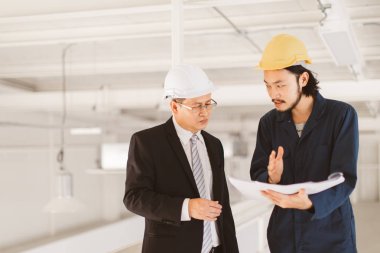 Asya çift mühendis ve genç bir mühendis blueprint görünüm ve birlikte, endüstriyel fabrika mühendisi için kavram tartışmak.