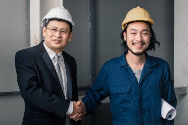 Asya çift mühendis ve genç bir mühendis blueprint görünüm ve birlikte, endüstriyel fabrika mühendisi için kavram tartışmak.