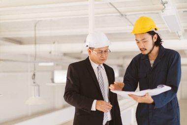 Asya çift mühendis ve genç bir mühendis blueprint görünüm ve birlikte, endüstriyel fabrika mühendisi için kavram tartışmak.