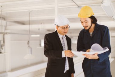 Asya yönetici mühendisi ve genç mühendis fabrika denetim, genç elinde plan ve birlikte tartışmak, sanayi fabrikasında mühendis için kavram.