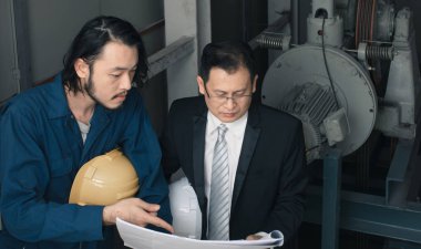 Asya çift mühendis ve genç bir mühendis blueprint görünüm ve birlikte, endüstriyel fabrika mühendisi için kavram tartışmak.