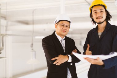 Asya yönetici mühendisi ve genç mühendis fabrika denetim, genç elinde plan ve birlikte tartışmak, sanayi fabrikasında mühendis için kavram.