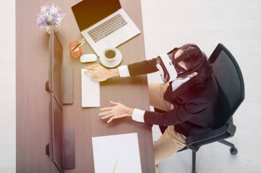 Sanal gerçeklik gözlüğü giyen genç Asyalı iş adamı üst görünümü, vizyonu test etmek için önünde iki elini tutun, yoğun yeni gadget gözden geçirme üzerinde çalışıyor, dizüstü bilgisayar ile, modern ofis arka plan