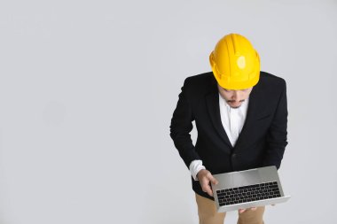 Mutlu, siyah takım elbise ve beyaz gömlek genç Asyalı iş adamı üst görünümü, sarı kask giyen, aşağı bakıyor ve elinde tablet ekranına dokunmadan, beyaz izole arka plan üzerinde