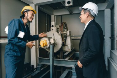 Asyalı mühendis ve genç mühendis yan yana durup gülümsüyor, elinde planlar, endüstriyel fabrikada mühendis konsepti var..