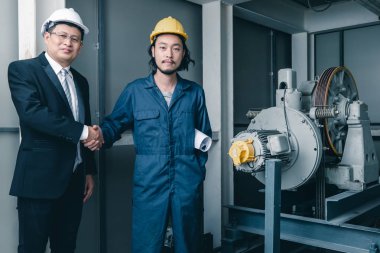 Asya çift mühendis ve birlikte duran genç bir mühendis ve kamera için gülümseme, büyük planı elinde, endüstriyel fabrika mühendisi için kavram tutar.