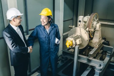 Asya çift mühendis ve birlikte duran genç bir mühendis ve kamera için gülümseme, büyük planı elinde, endüstriyel fabrika mühendisi için kavram tutar.