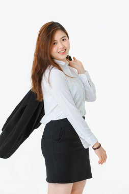 Beyaz gömlekli genç, güzel, çekici Asyalı bayanın tam uzunlukta stüdyo portresi, bir kolunda iş elbisesi, kalçada el, profesyonel poz, kameraya bakma, izole beyaz arka plan üzerine