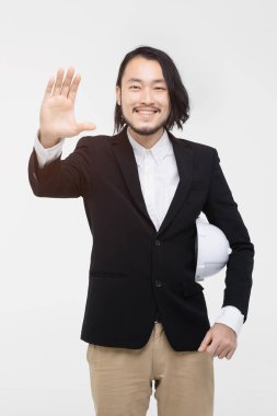 Mühendisportresi, siyah takım elbiseli, elini sallayan, kolunda beyaz kask, ayakta, arkasında beyaz arka plan.