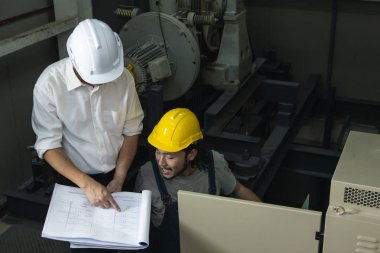 , çok uzak Orta yaş Asya fabrika yöneticisi ve genç Asya mühendisi kot tulum, güvenlik ayakkabıları, kask üretim tesisinin çatısında bir şey noktası