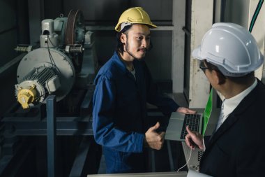 , çok uzak Orta yaş Asya fabrika yöneticisi ve genç Asya mühendisi kot tulum, güvenlik ayakkabıları, kask üretim tesisinin çatısında bir şey noktası