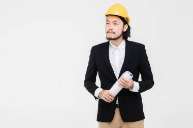 Mühendisportresi, siyah takım elbiseli, başında sarı kask, ayakta, o yan bakıyor, elinde plan, arkasında beyaz arka plan.