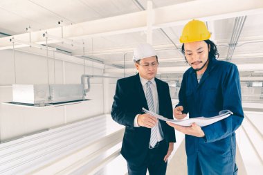 Asya çift mühendis ve genç bir mühendis blueprint görünüm ve birlikte, endüstriyel fabrika mühendisi için kavram tartışmak.