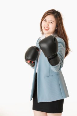 Genç yakın çekim stüdyo portre, güzel, çekici Asyalı bayan, açık mavi iş elbisesi içinde, siyah deri boks eldivenkoymak, eğlenceli mücadele eylem için poz, izole beyaz arka plan üzerinde