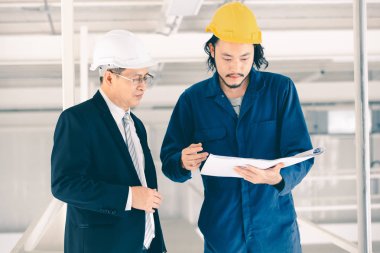 Asya çift mühendis ve genç bir mühendis blueprint görünüm ve birlikte, endüstriyel fabrika mühendisi için kavram tartışmak.