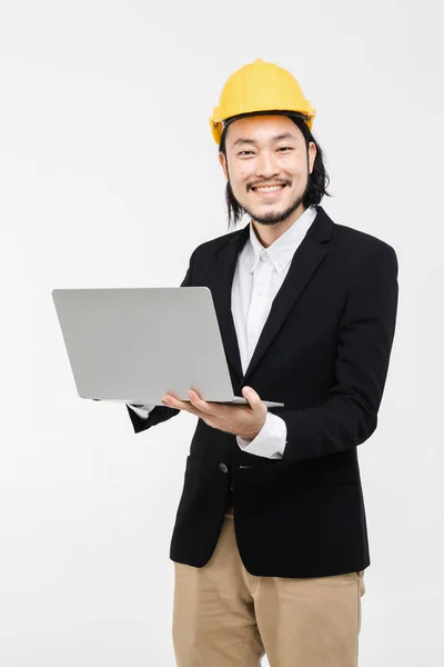 アジアのエンジニアの肖像画は 黒いスーツを着て 彼の頭の上に黄色のヘルメット 立って 彼の腕にノートブックを保持し それを使用して 彼の後ろに白い背景 — ストック写真