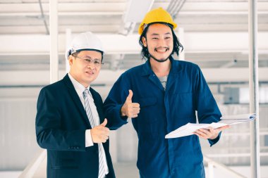 Asya çift mühendis ve birlikte duran genç bir mühendis ve kamera için gülümseme, büyük planı elinde, endüstriyel fabrika mühendisi için kavram tutar.