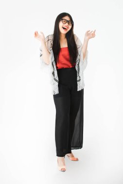 Genç çekici Asyalı kadın tam uzunlukta stüdyo portre, uzun siyah saçlı, gözlük giyen, rahat moda, yüksek topuk, neşeyle poz ve kamera bakarak, izole beyaz arka plan üzerinde