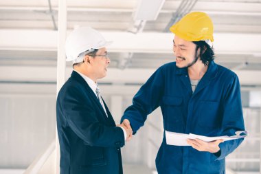 Genç Asyalı mühendis endüstriyel fabrikada yönetici mühendis ile tokalaşıyor, taslak genç mühendis eli, patron konsepti endüstriyel fabrikayı ziyarete geliyor.