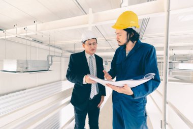 Asya çift mühendis ve genç bir mühendis blueprint görünüm ve birlikte, endüstriyel fabrika mühendisi için kavram tartışmak.