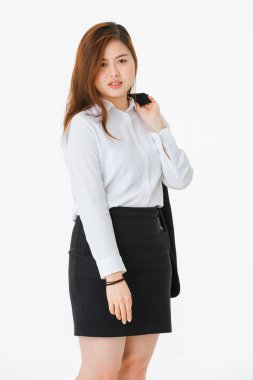 Beyaz gömlekli genç, güzel, çekici Asyalı bayanın tam uzunlukta stüdyo portresi, bir kolunda iş elbisesi, kalçada el, profesyonel poz, kameraya bakma, izole beyaz arka plan üzerine