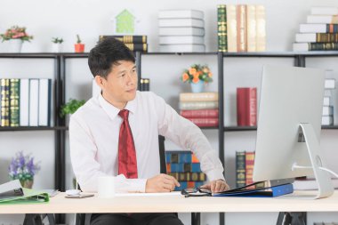 Onun çalışma alanı başlangıç ofis, bilgisayar ve ofis arka plan ile çalışan orta yaşlı, yakışıklı, Asya, işadamı, koyu kırmızı kravat, Beyaz gömlekli portresi,