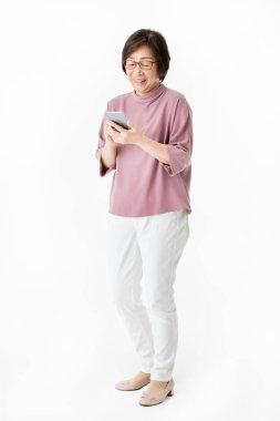 Yaşlı Asyalı kadın akıllı telefon ekran arıyor ve kafa karıştırıcı ve endişe hissediyorum gibi görünüyorsun. Yaşlı insanların teknoloji öğrenimi için konsept. Stüdyo çekimi beyaz arka planda izole.