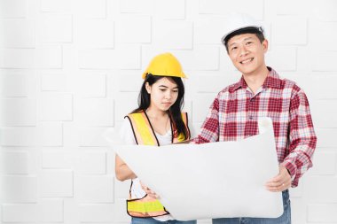 Kask, blueprint kontrol portakal, sarı yansıtıcı Emanet yelek ve kask, giyen genç kadın Asya asistanı, öğretim giyen orta yaşlı Asya mimar, kot pantolon ve ekose desenli gömlek,