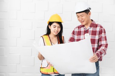 Kask, blueprint kontrol portakal, sarı yansıtıcı Emanet yelek ve kask, giyen genç kadın Asya asistanı, öğretim giyen orta yaşlı Asya mimar, kot pantolon ve ekose desenli gömlek,