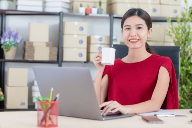 Orta yaşlı Asyalı, iş adamı, gözlüklü, beyaz tişörtlü, çalışma yerinde, ofisinde duruyor, gülümsüyor, memnun ve kendinden emin bir şekilde işe girişinden, ofis geçmişinden,