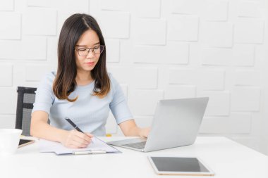 Genç, güzel, Asya mimar, giyen gözlük Oda kalem elinde, Toplantı inşaat sahasında alarak not notepad, defter ile üzerinde çalışma tablet ve smartphone ve kahve Kupası arka plan