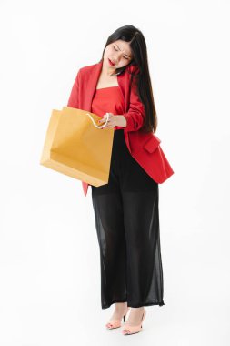 Genç çekici Asyalı kadın tam uzunlukta stüdyo portre, uzun siyah saçlı, gözlük giyen, rahat moda, akıllı telefon konuşmak, endişeyle alışveriş çantası içine bakmak, izole beyaz arka plan üzerinde