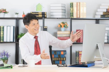 Onun çalışma alanı başlangıç ofis, bilgisayar ve ofis arka plan ile çalışan orta yaşlı, yakışıklı, Asya, işadamı, koyu kırmızı kravat, Beyaz gömlekli portresi,