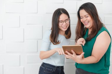 Genç, tombul, güzel, Asyalı bayan tutma ve tablet işaret Portresi, genç, sevimli, Asyalı bayan, ofis yönetim kurulu, beyaz tuğla duvar arka plan üzerinde konuşurken zevk